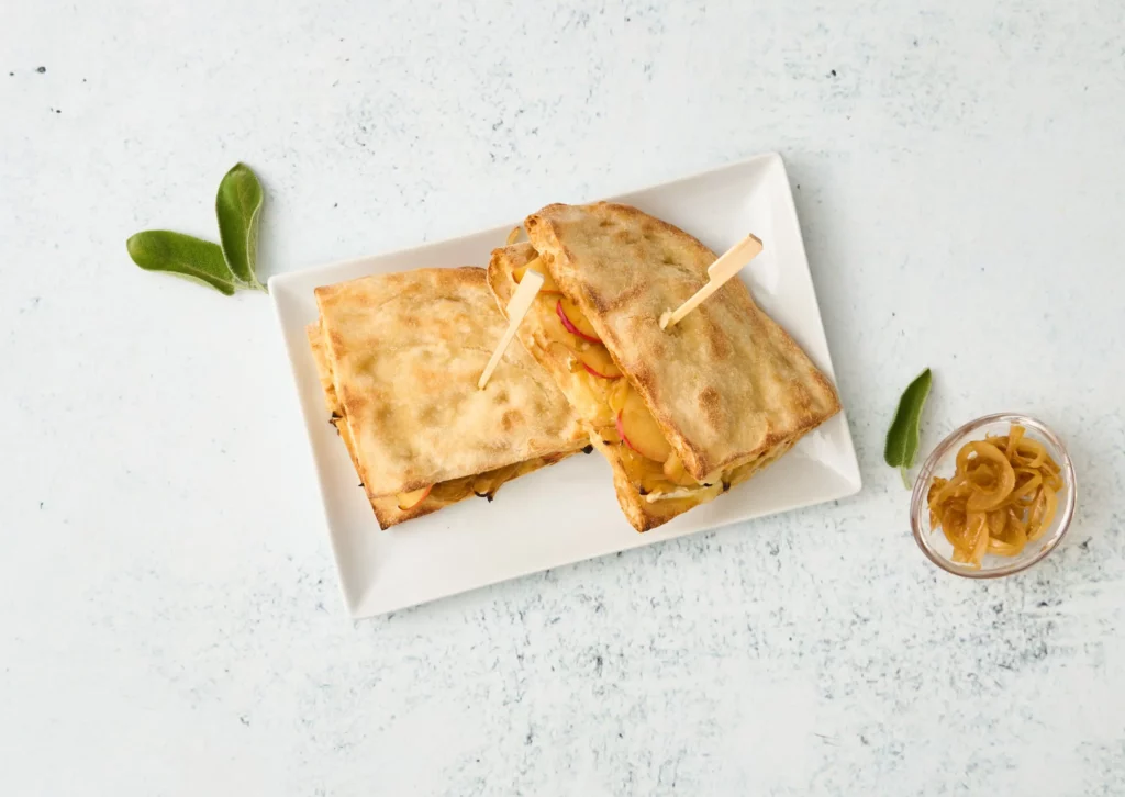 PinsaPanino con cipolle caramellate, brie, mele e salvia